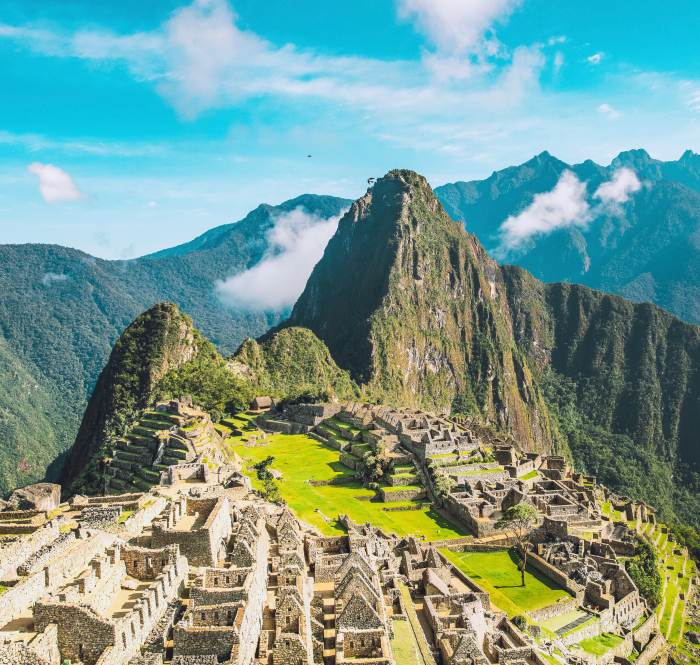 The stone ruins of Machu Picchu form neat grids of streets and houses terraced along the peak of a mountain.