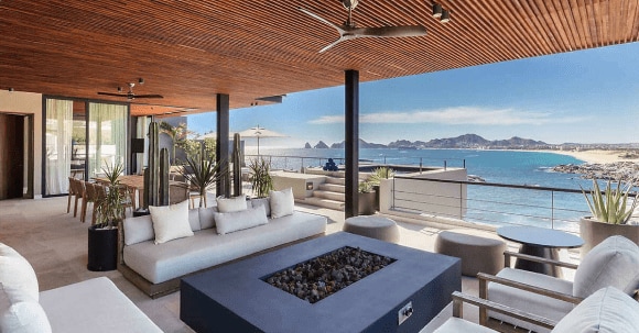 The living area of a penthouse villa at The Cape, a Thompson Hotel. The patio includes extensive seating as well as a fire pit.