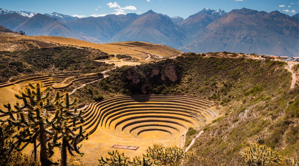 The Sacred Valley includes a terraced bowl following the contours of the surrounding hillside. The landscape is brown and dusty in the sun.