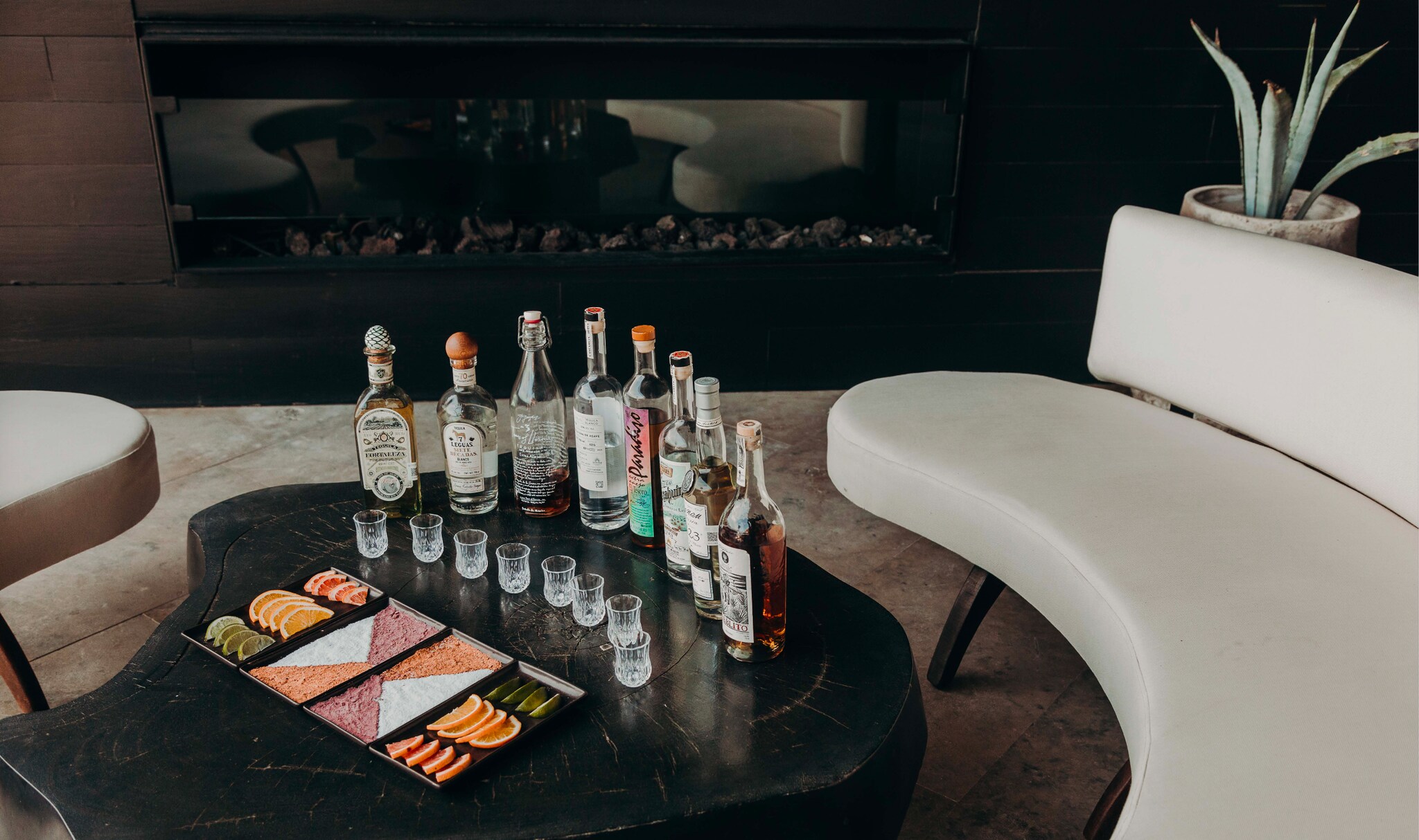 Row of tequila bottles, shot glasses, and snacks