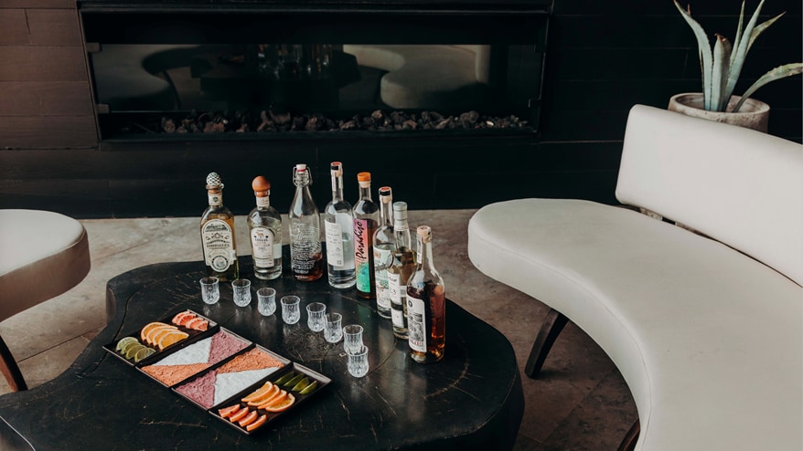 Row of tequila bottles, shot glasses, and snacks