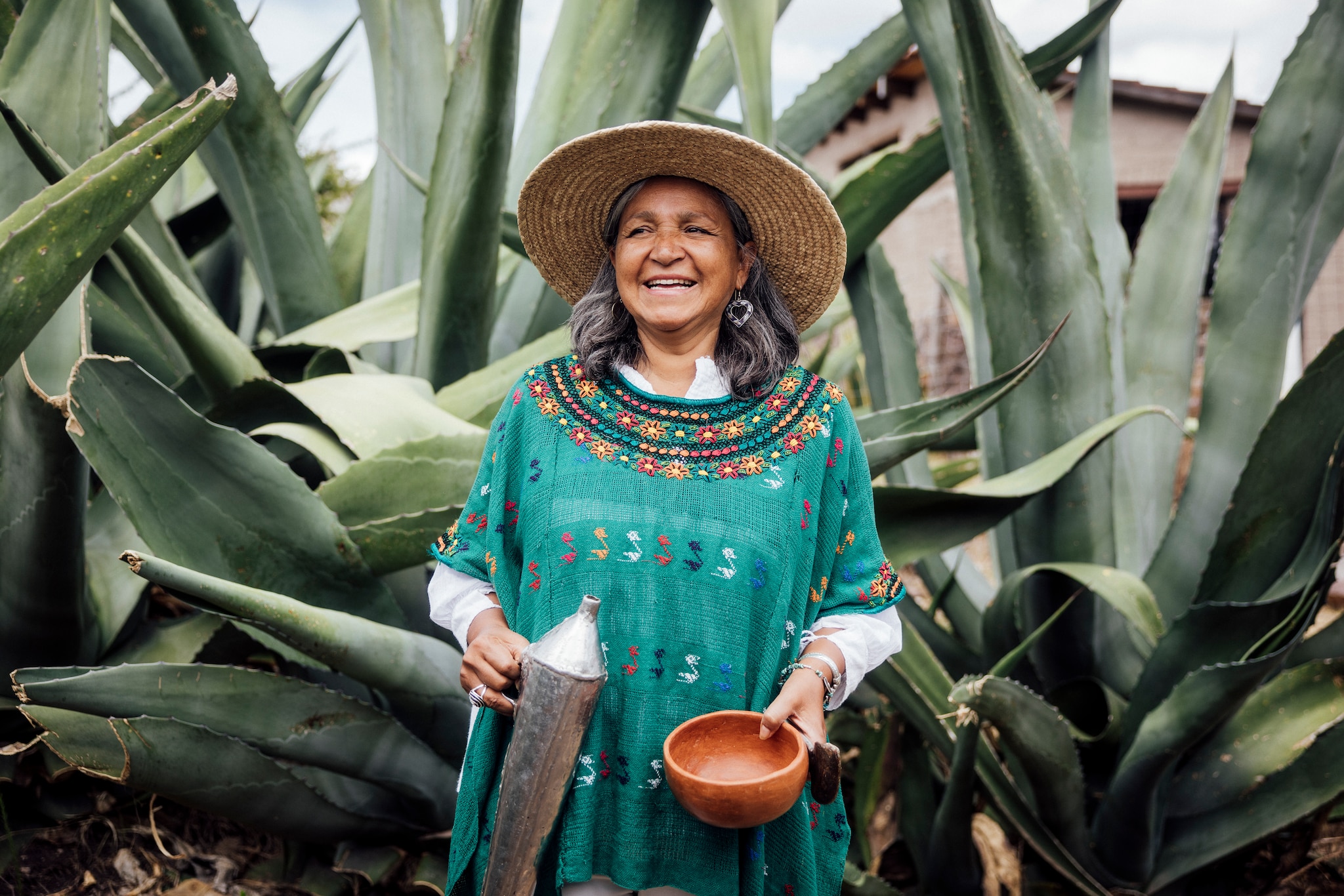 woman standing among agave plants with pitcher and bowl