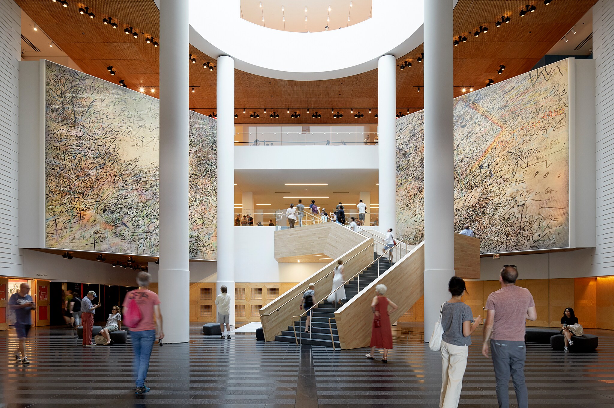 Inside the museum, white columns surround a central light well. Huge pictures with scribbles on a multicolored background flank a staircase.