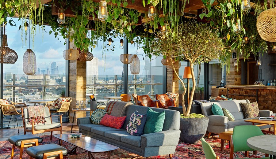 The Nest rooftop bar provides casual seating, amidst lush hanging plants and floor-to-ceiling windows with views of the city.
