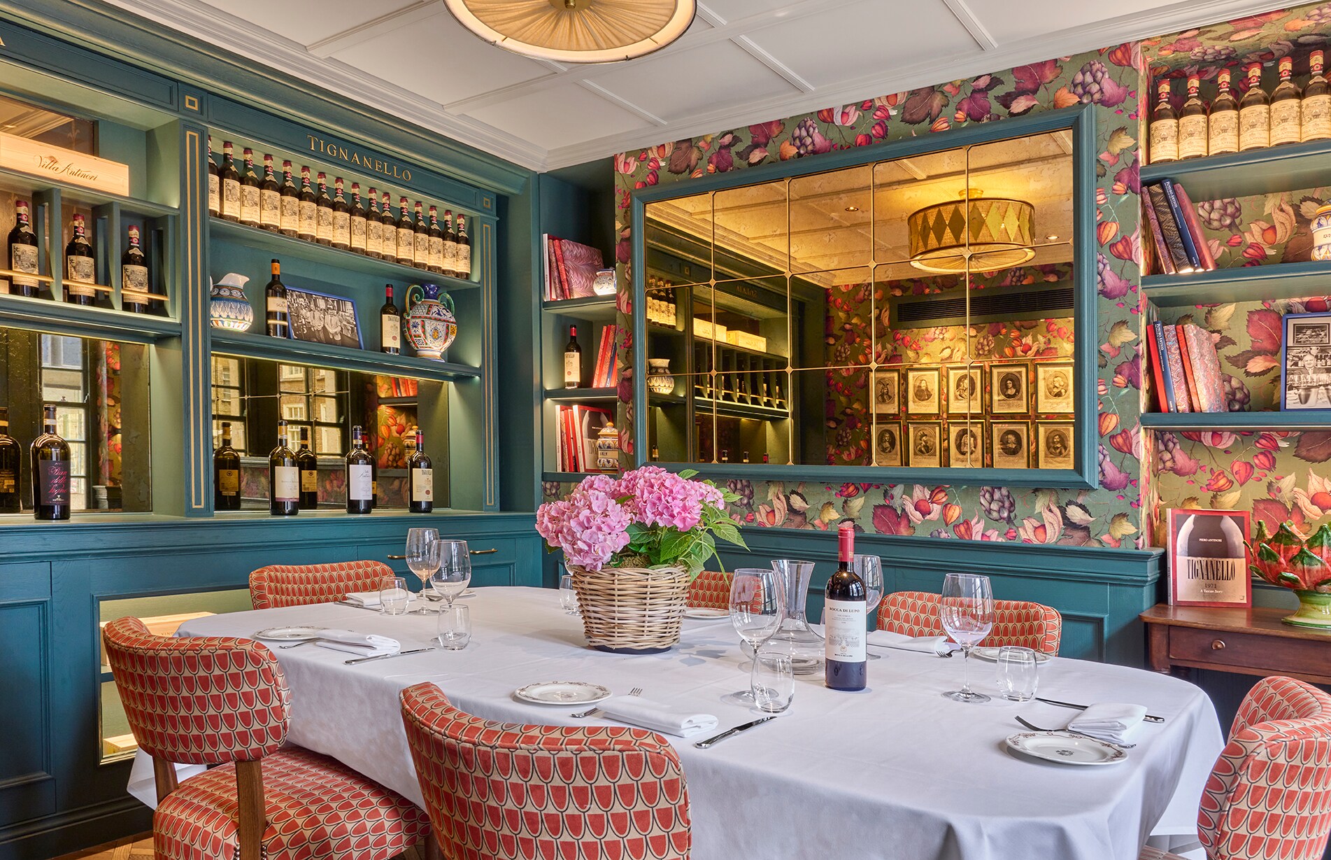  In a corner of Cantinetta Antinori, a dining table for six is surrounded by teal and pink décor and bookshelves crowded with wine.