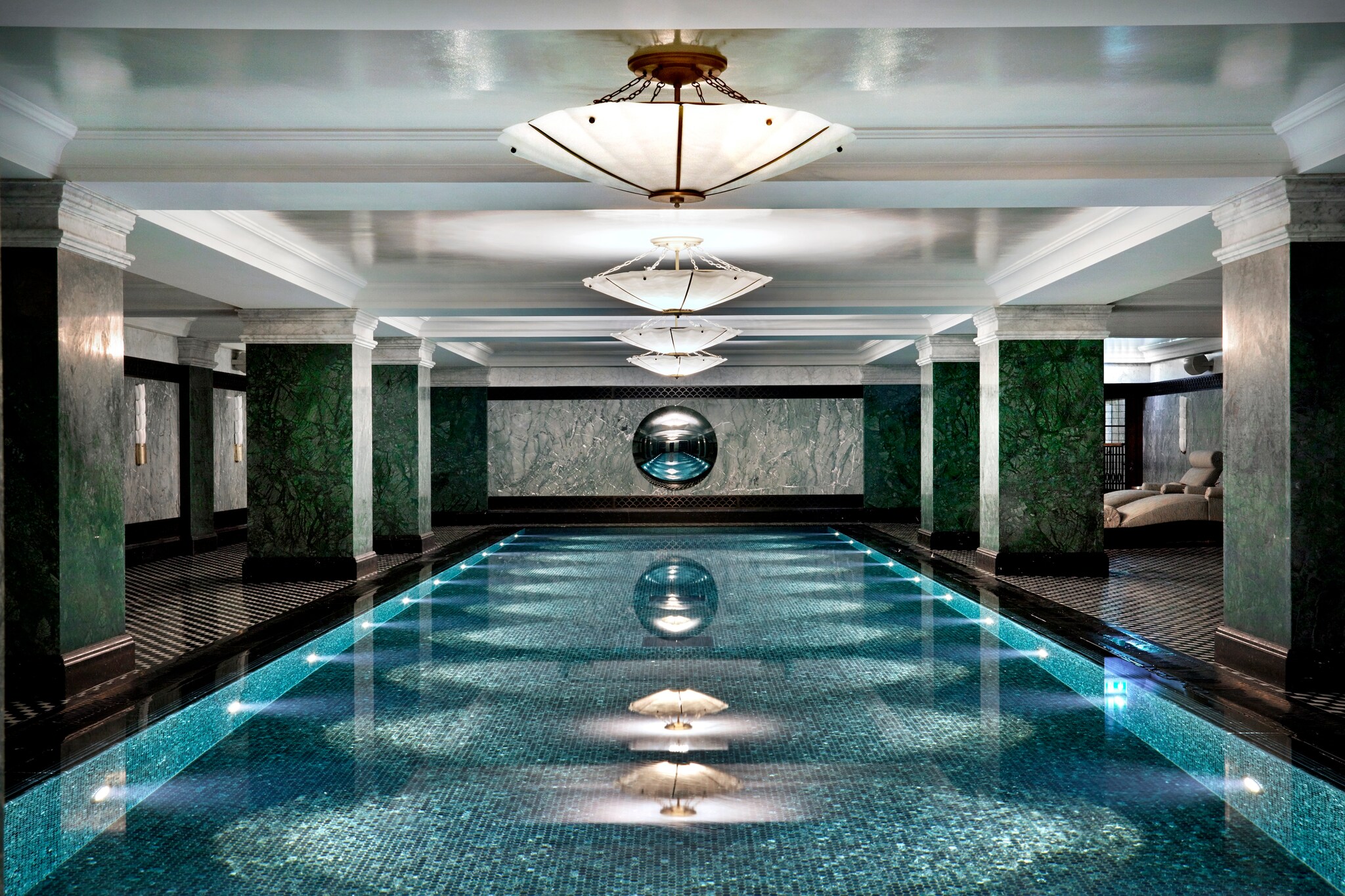 The Ned’s Club Spa pool is large enough for laps, with a mosaic tile finish inside and dark green pillars surrounding it.