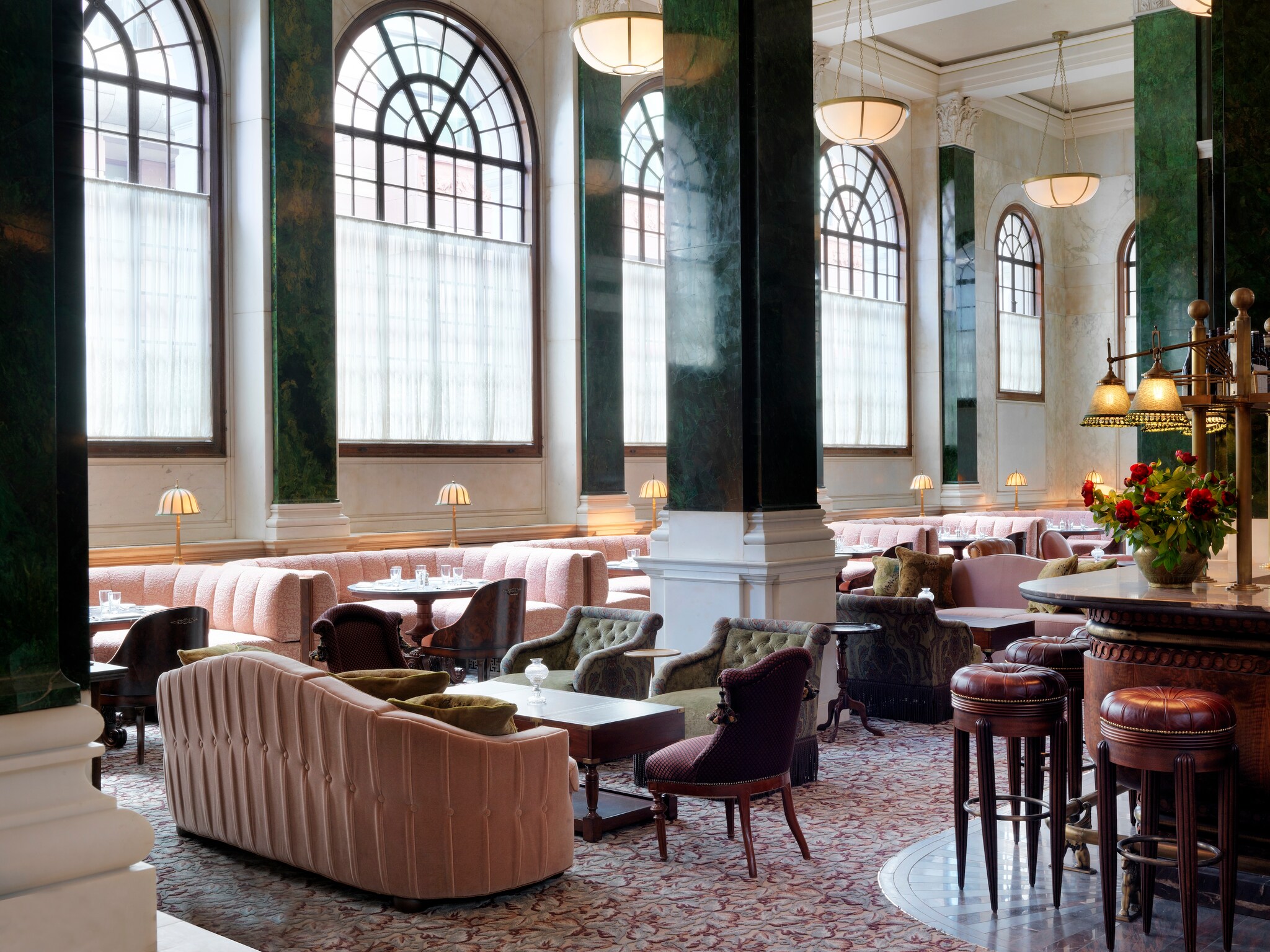 In Millie’s Lounge, plush light pink couches are arranged into booths and nooks under high ceilings and dark-green pillars.