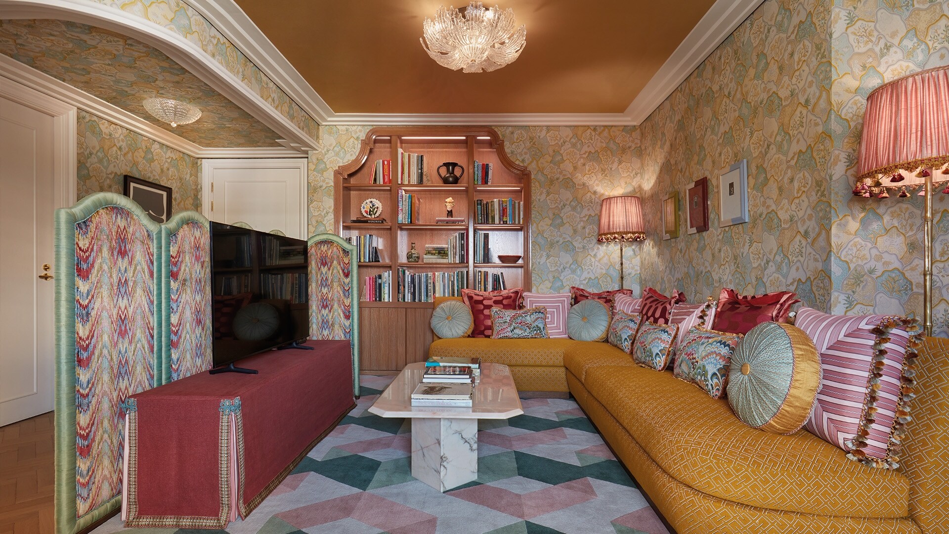 The lounge of the Penthouse is covered in riotous patterns in gentle pastels, the wallpaper to the long L-shaped couch to the folding screen.