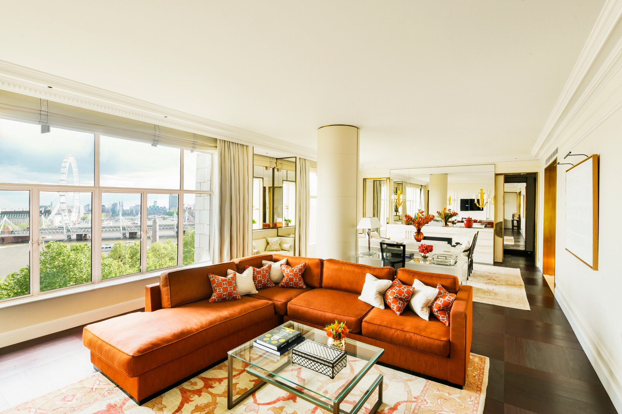 In one of the hotel’s premium suites, a large red L-shaped couch creates a nook in front of a window overlooking the London Eye.