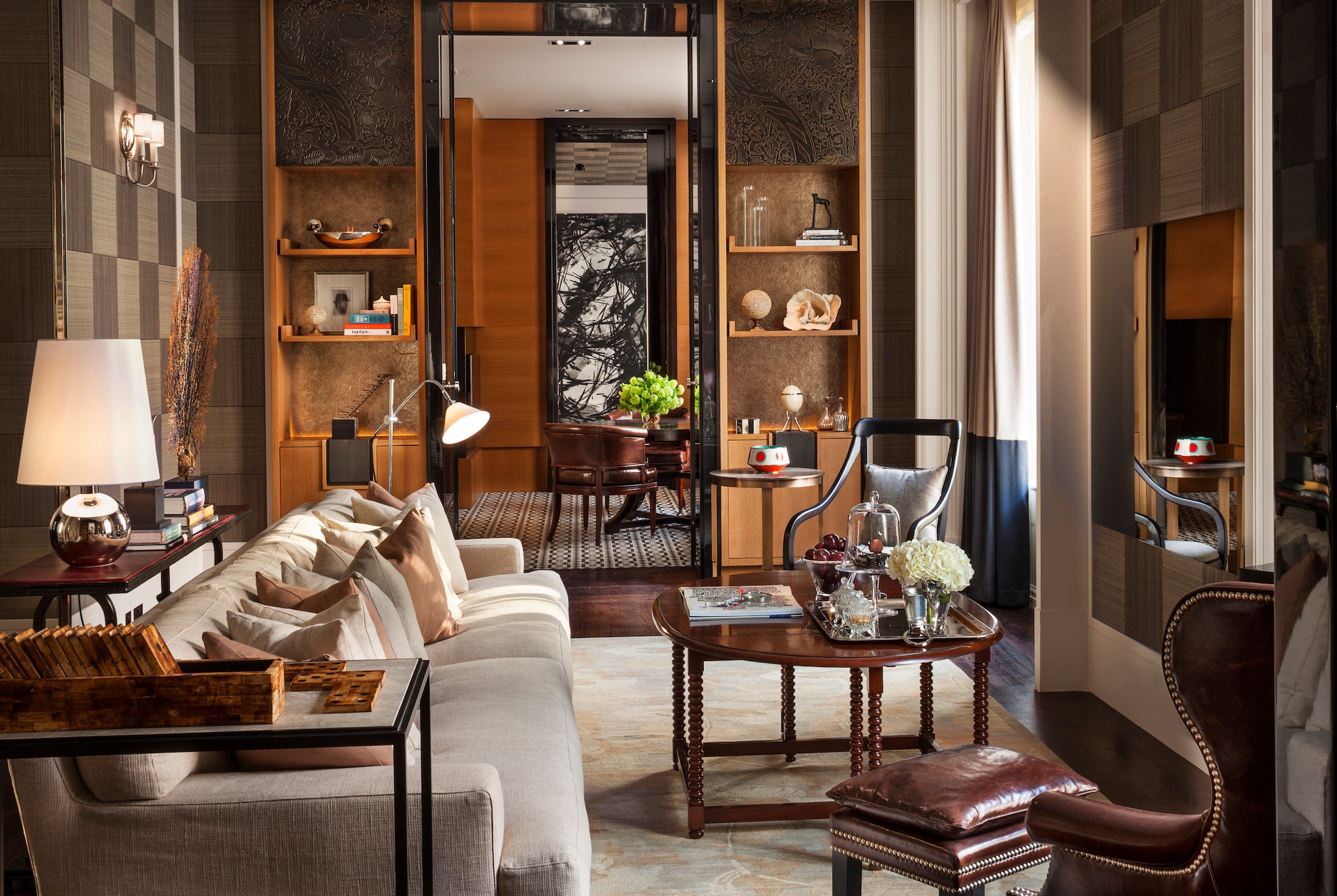 In the Manor House suite, a long living room with an amply-cushioned couch leads in the distance to a room with a large table and chairs.
