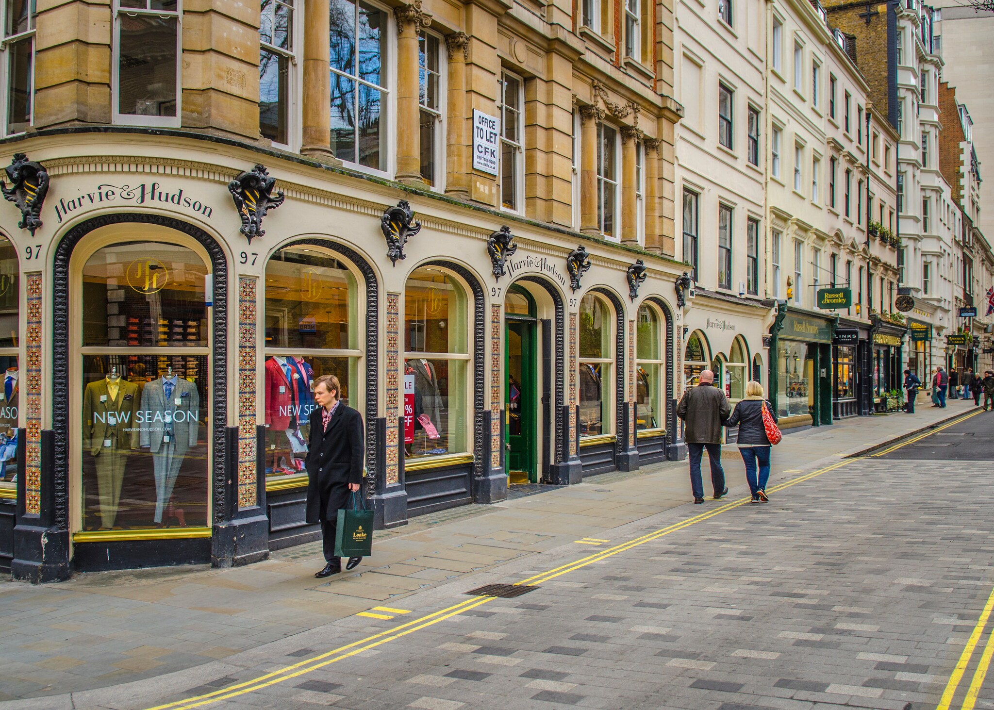 On the corner of Jermyn street, looking at the Harvie & Hudson storefront filled with suits, down the street filled with shops.